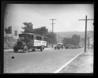 Automobiles following bus with sign reading "California Caravan New York to Santa Monica," Calif., circa 1930
