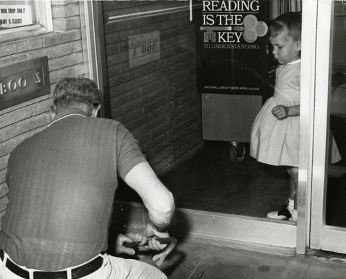 Small child watching the removal of 1950 Lancaster Library plaque from the Fig Avenue location, Lancaster, California