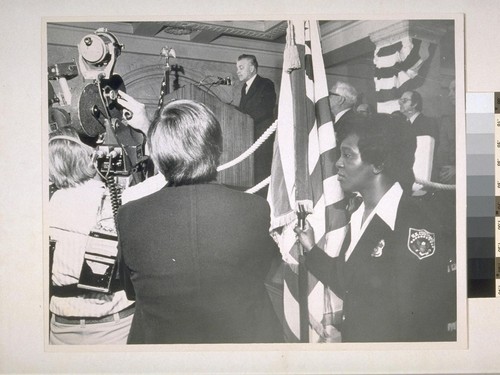 Audrey Haynes, customs patrolman, guards flay at right as cameras cover Vernon D. Acree, U.S. Commission of Customs