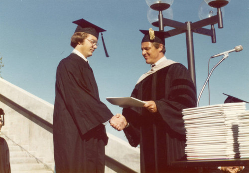 President Banowsky presenting a diploma to a graduate