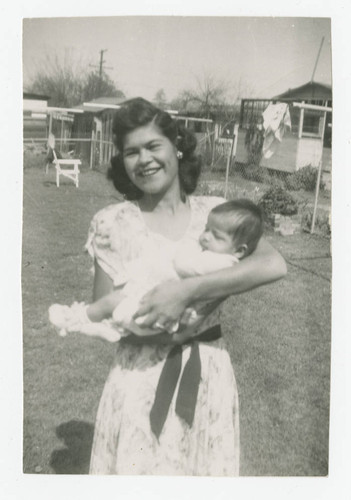 Mary Barajas with infant Esther Barajas in the backyard of a house, Los Nietos, California