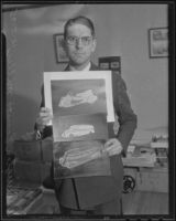 W. E. Miller, automobile designer, holds up illustrations of 3 car designs, Los Angeles, 1935