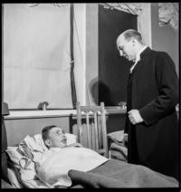 Military Hospital in Vaasa. Lutheran pastor Rev, Daniel Still at bedside of Niilo Maatta, wounded at battle near Lipola [Christmas service for wounded soldiers]