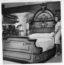 Mrs. Kris Rouard shown standing beside the bed in which Ulysses S. Grant slept at the old Golden Eagle Hotel which stood at the corner of 675 K Street until 1962