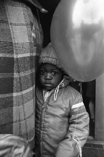 Child at Ritter Elementary School holding a balloon, Watts (Los Angeles, Calif.), 1983