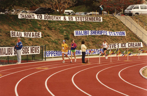 Runners on the track--in the background the hillside with banners