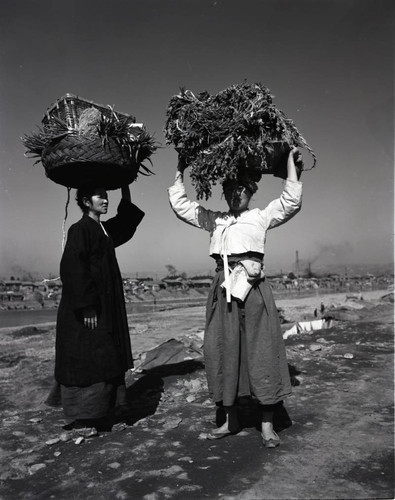 Two women with posing with loads on their heads