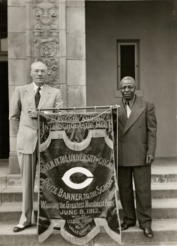 Herb Whitted and Stonewall Jackson hold replica of United States Track Championship Banner of 1912