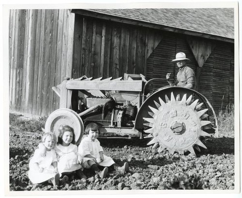 Man and girls posing with a tractor