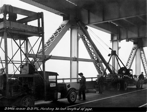 [Employees of W. E. Thomas Welding Company hoist 30 foot length of pipe into place on Bay Bridge]