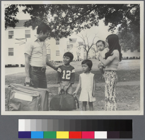 Family with three children holding suitcases