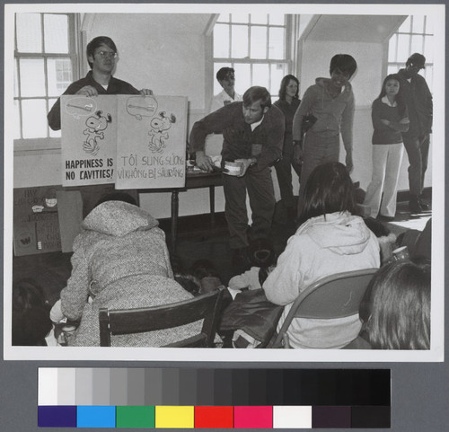 Man holding up "Happiness is no cavities!" sign to teach refugees about dental care