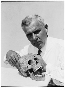 Man near a human skull at the Pacific Southwest Museum