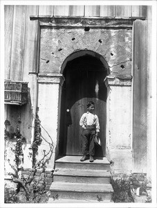 Boy standing in the back entrance to Mission San Juan Bautista, California, ca.1903