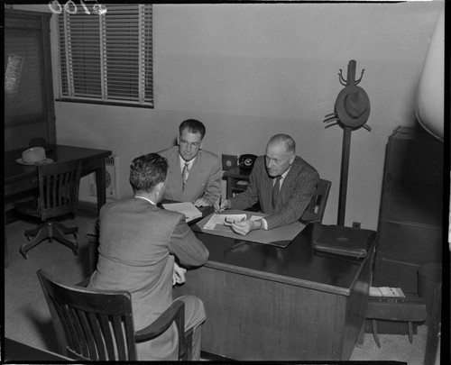 Three men going over paperwork at a desk