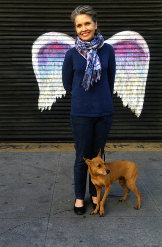 Unidentified woman wearing a plaid scarf posing in front of a mural depicting angel wings