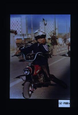 Poster depicting a young boy on a mini-motorcycle