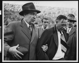 Notre Dame football coach Frank Leahy and University of Southern California football coach Jeff Cravath walking off the field together after game at Los Angeles Coliseum (waist high shots), 1947