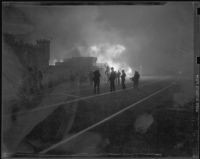 People rushing from burning structures at Castle Rock Beach, Los Angeles, 1938