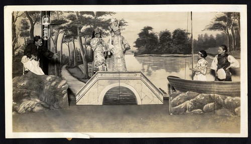 Two men on a bridge talk with two women in a boat /