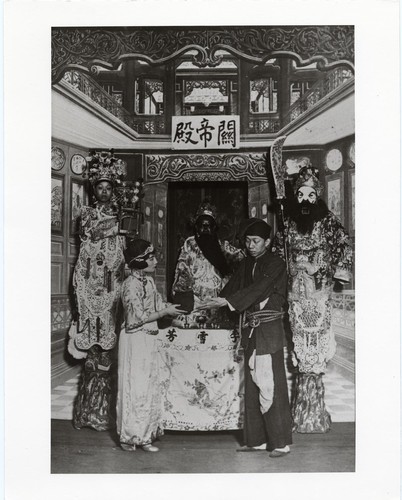 In the temple of General Kwan the actor Li Hsueh-fang officiates as a young couple exchange gifts before him /