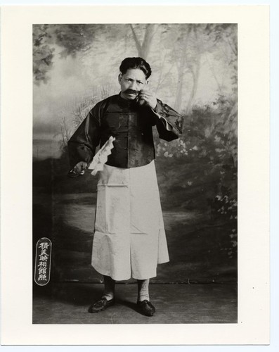 Mustached actor in modern Chinese dress, black jacket and a long gown /