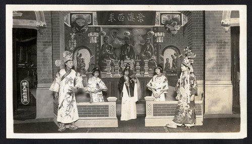 Three women stand before an altar, one woman holds a fly whisk, two men flanking, staged at the Great Star Theatre /