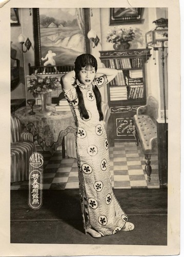 Actress dressed in floorlength cheongsam adjusts her hair /