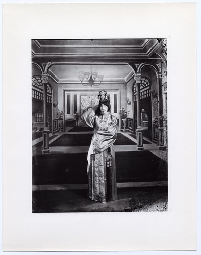 Actress standing in classical dress with water sleeves with a backdrop of a mansion interior /