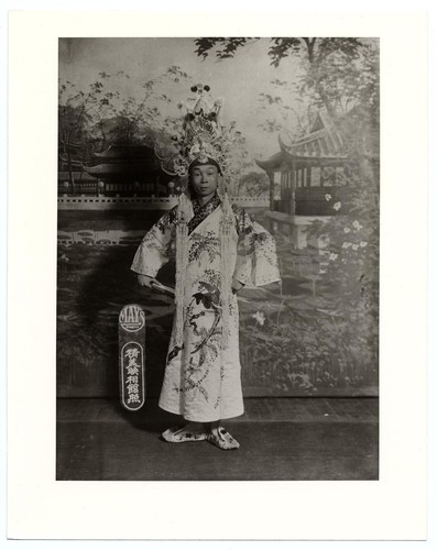 Portrait of a standing actor in the role of a scholar in classical dress in garden setting /