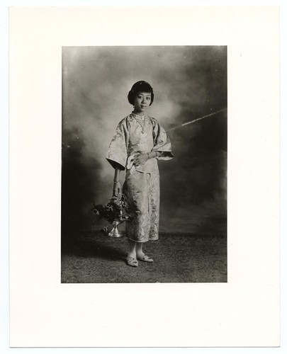 Studio portrait of an actress holding a silver basket of flowers /