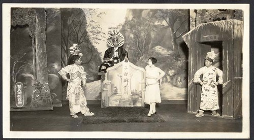 Woman in 20's style dress with 3 men in Chinese costume at a tomb, staged at the Great Star Theatre /