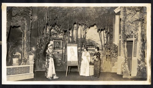 Woman paints a self-portrait, a lady attendant and scholar look on, staged at the Great Star Theatre /