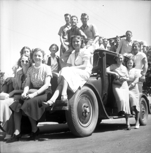 [16 students posed on an old car]