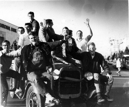 [Students sitting on car at Homecoming]