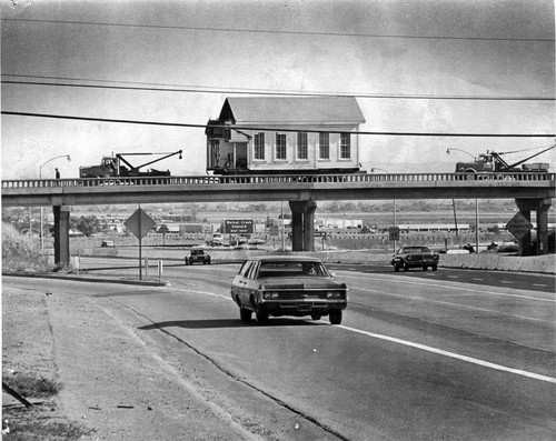 Highway view of moving wing of Old Murray School to cemetery location (1975), photograph