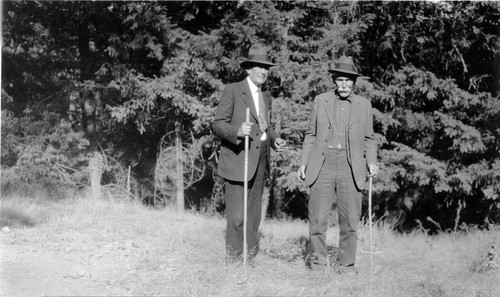 Roger "Rod" Fallon (1853-1932) and an unidentified man standing in a meadow, (c. 1929), photograph