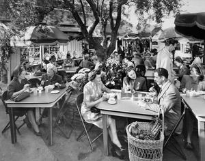 Shoppers eating at outdoor tables at what looks like the Farmer's Market in Los Angeles, ca.1940-1949