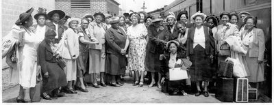 Group photograph of club women standing next to railroad car