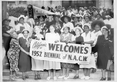 Group photograph of women holding "California welcomes 1952 biennial of N.A.C.W." banner