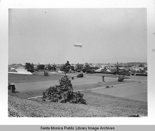 Dirigible (airship) hovers over the camouflage designed by landscape architect Edward Huntsman-Trout during World War II to cover the Douglas Aircraft Company plant in Santa Monica, Calif