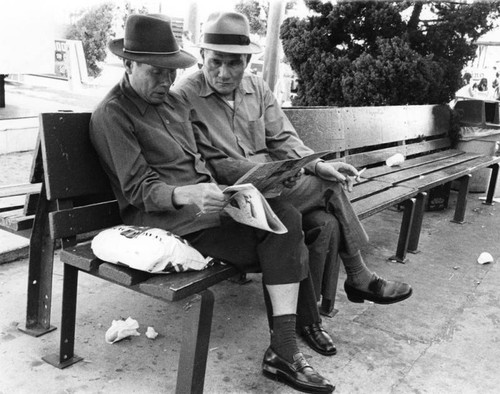 Two men reading a Chinese newspaper