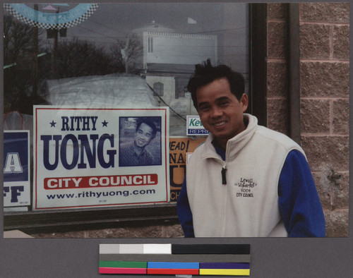 Rithy Uong standing by his city council campaign poster, Lowell, Massachusetts