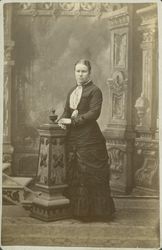 Portrait of an unidentified young woman standing at the foot of a flight of stairs