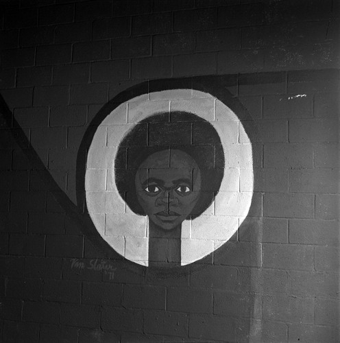 Mural painted on inside arena wall depicting a front view African American face surrounded by a white circle