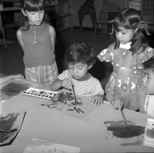 Seated boys paint while two girls look on