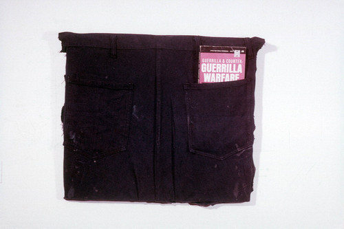 Mixed media assemblage: guerilla warfare book in the back pocket of a pair of pants