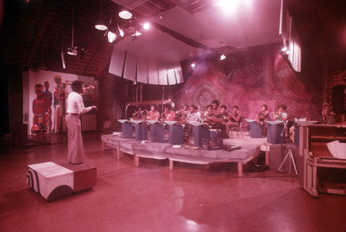 CAA orchestra on a stage with murals in the background