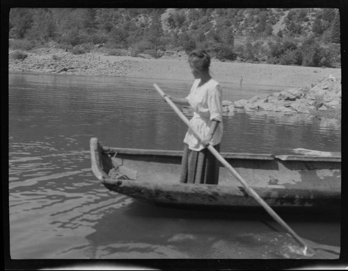 An unidentified Native American woman standing in canoe, with paddle