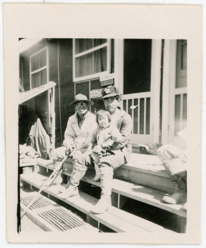 Men and child sitting on barrack stairs
